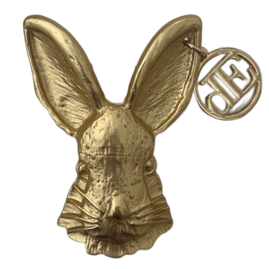 Gold rabbit-shaped keychain with a visible brand logo on a white background