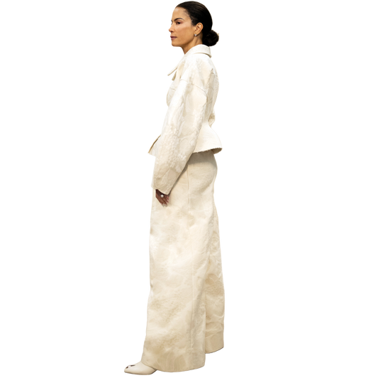 Woman in a white outfit standing in a room with beige walls and a white floor.