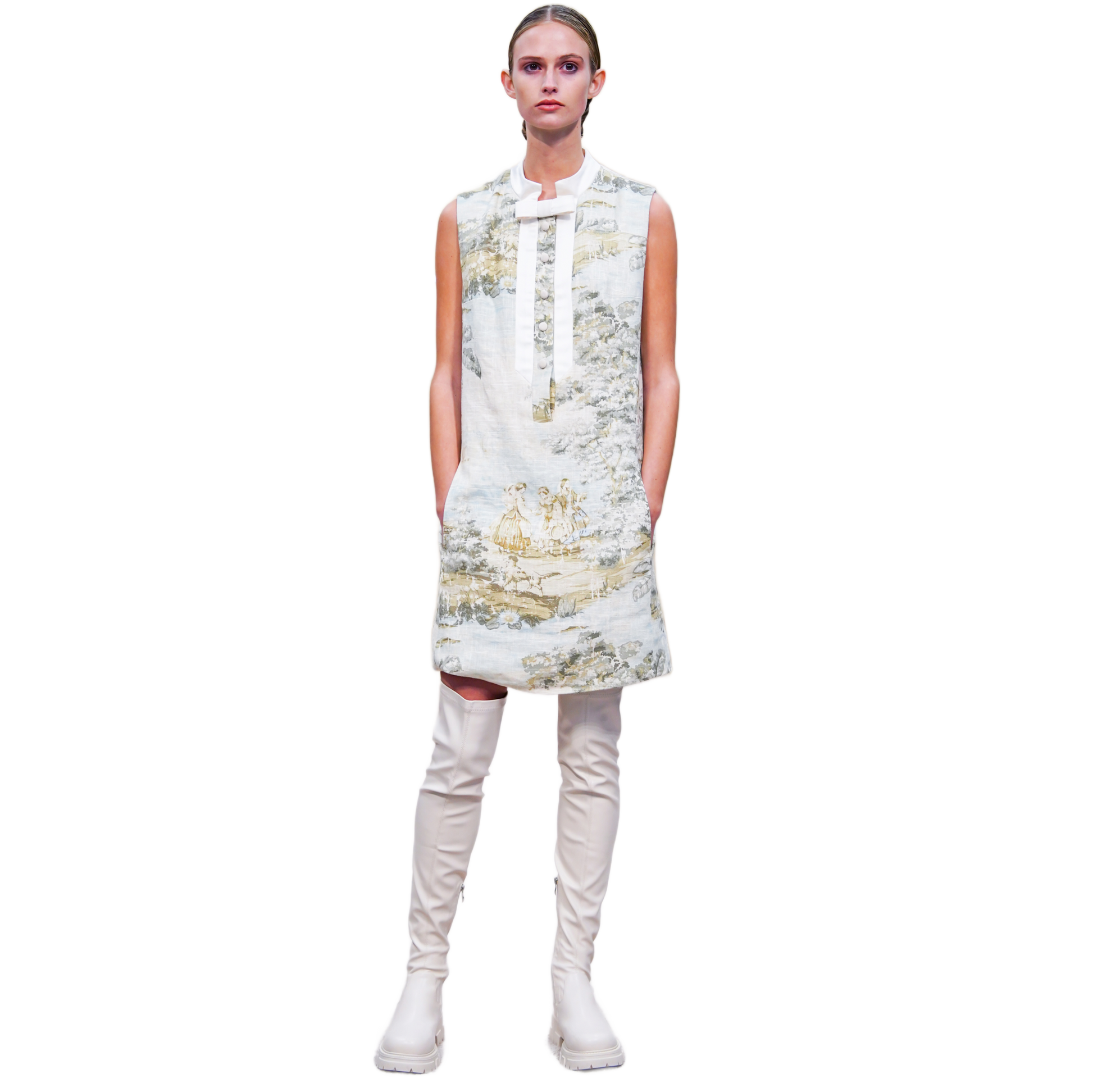 Model wearing a sleeveless floral dress with white knee-high boots on a white background