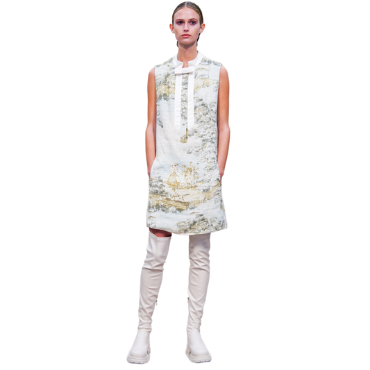 Model wearing a sleeveless floral dress with white knee-high boots on a white background
