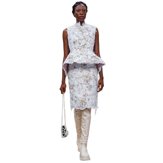 Woman wearing a floral peplum top and skirt with beige boots on a white background